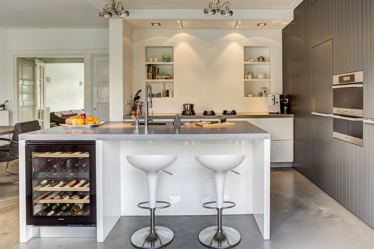 Heite-interieurbouw-Villa-Heemstede-keuken-op-maat-met-eiland-ingebouwde-wijn-koelkast-kastenwand-met-inbouwapparatuur-en-grijs-natuursteen-keukenblad